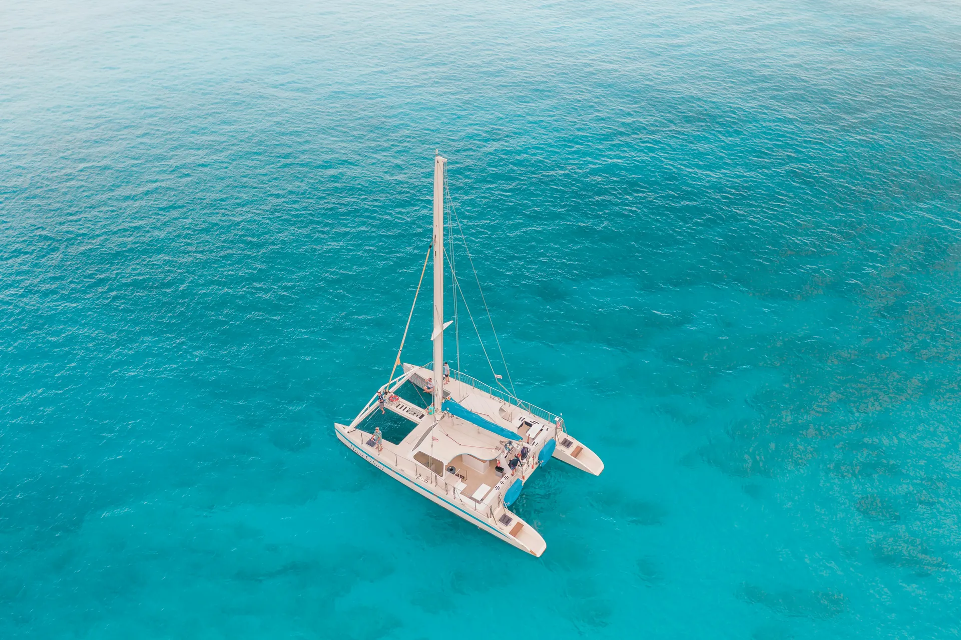 Stunning aerial view of a catamaran sailing in crystal clear turquoise waters.
