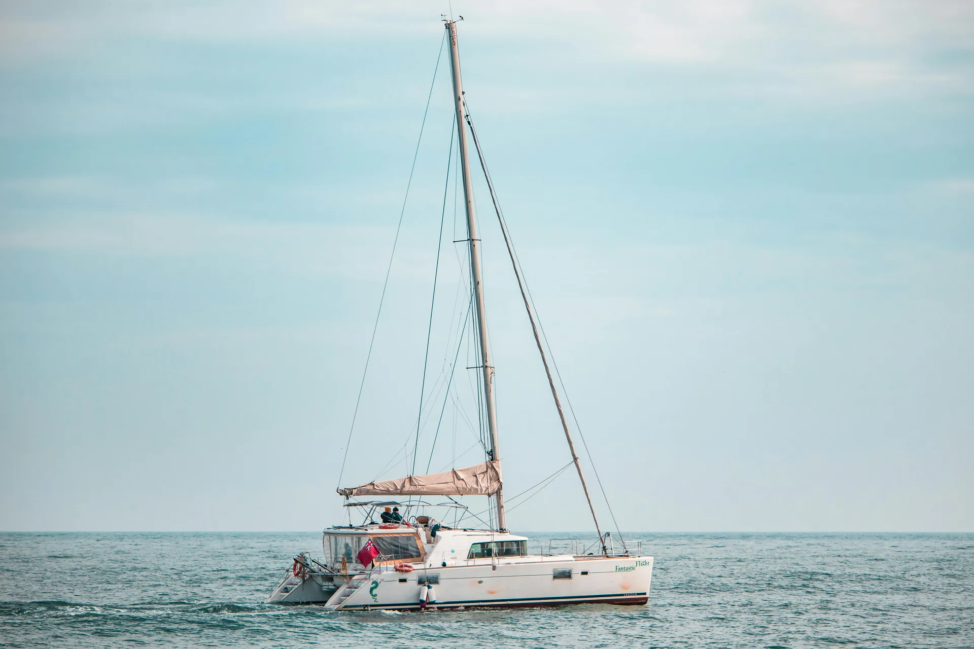 A catamaran sails peacefully on the tranquil sea under a pastel sky, perfect for leisure and escape.